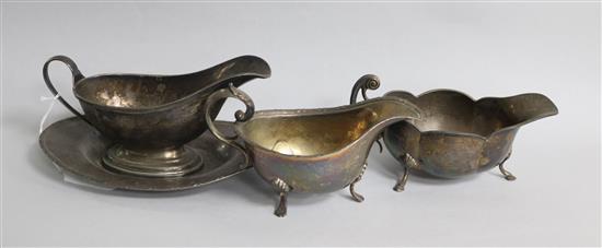 A silver sauceboat on stand and two other silver sauceboats.